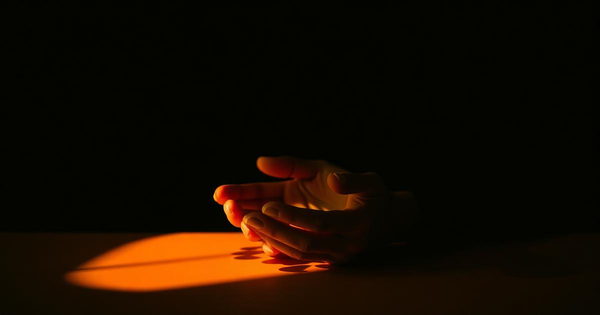 Open hands resting in warm lamplight against a dark background
